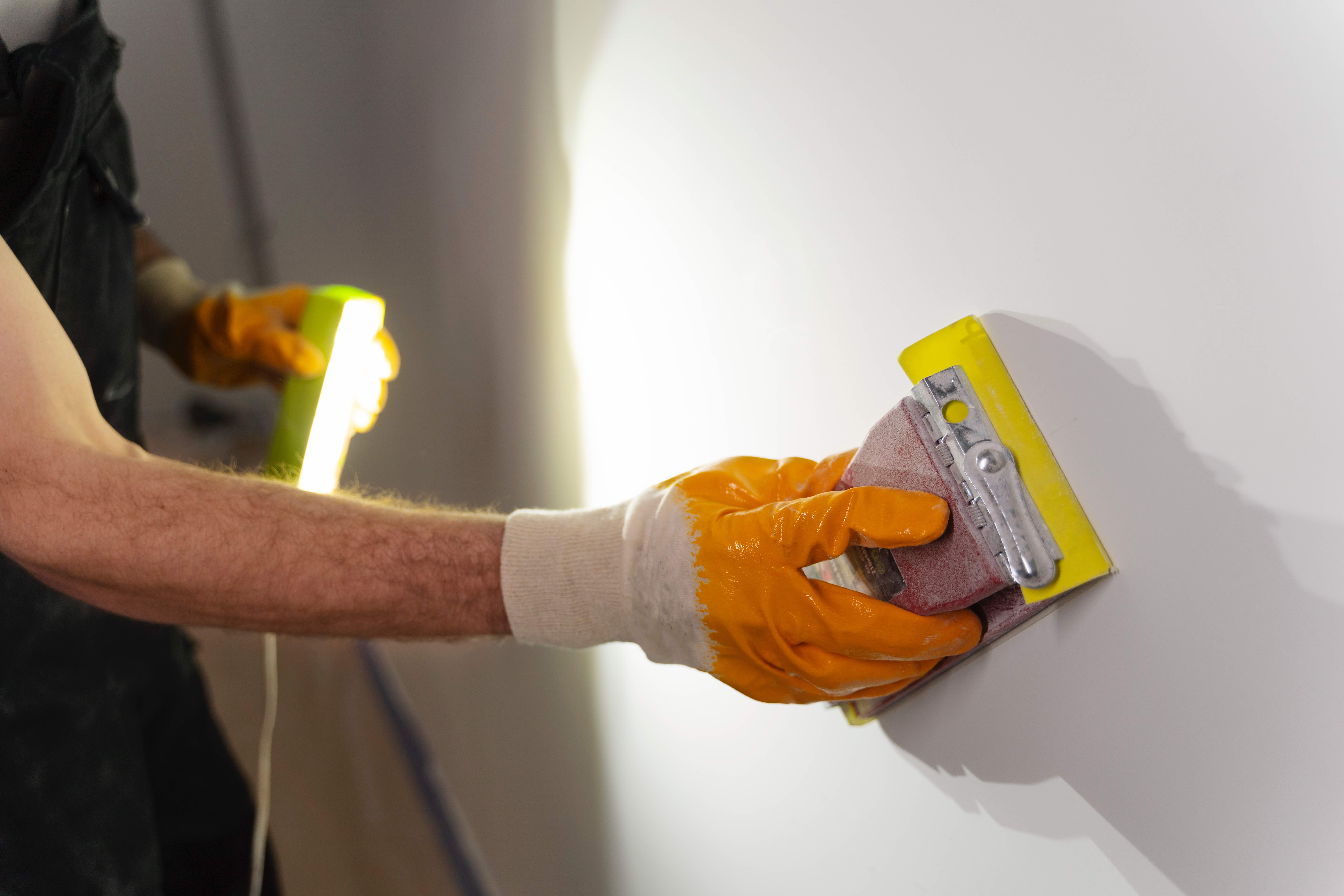 Construction worker sanding and finishing plastered wall