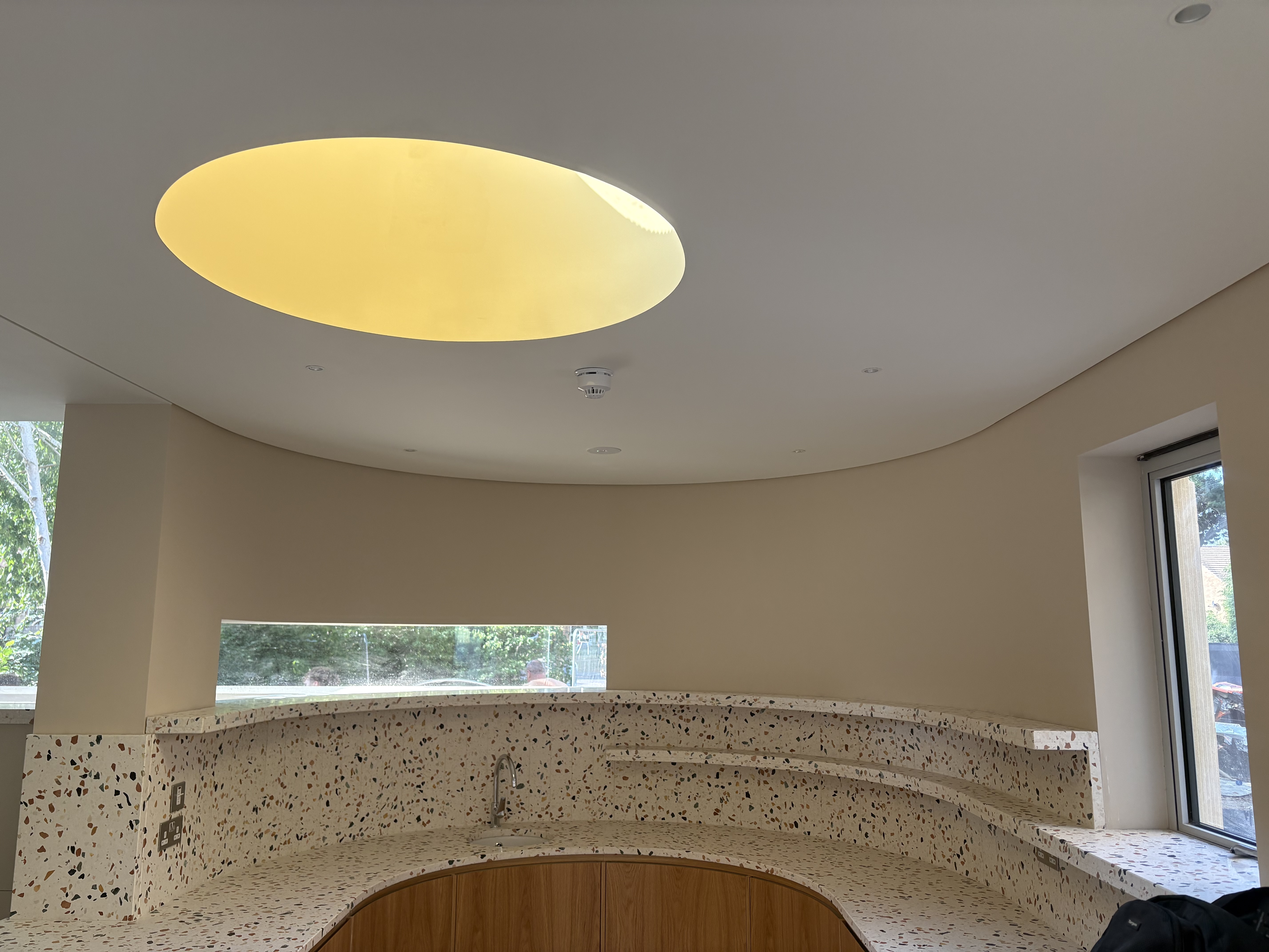 Finished curved kitchen with oval ceiling light and terrazzo countertops